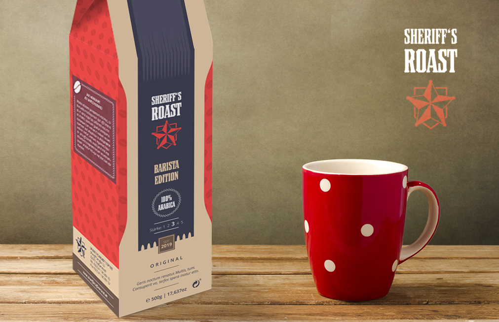 Een zak Sheriffs Roast Barista Edition koffie, met een onberispelijk Verpackungsdesign met zijn rode en beige kleuren en sterlogo, staat naast een rode mok met witte stippen op een houten oppervlak. De effen, gedempt groene achtergrond versterkt de stijlvolle uitstraling.